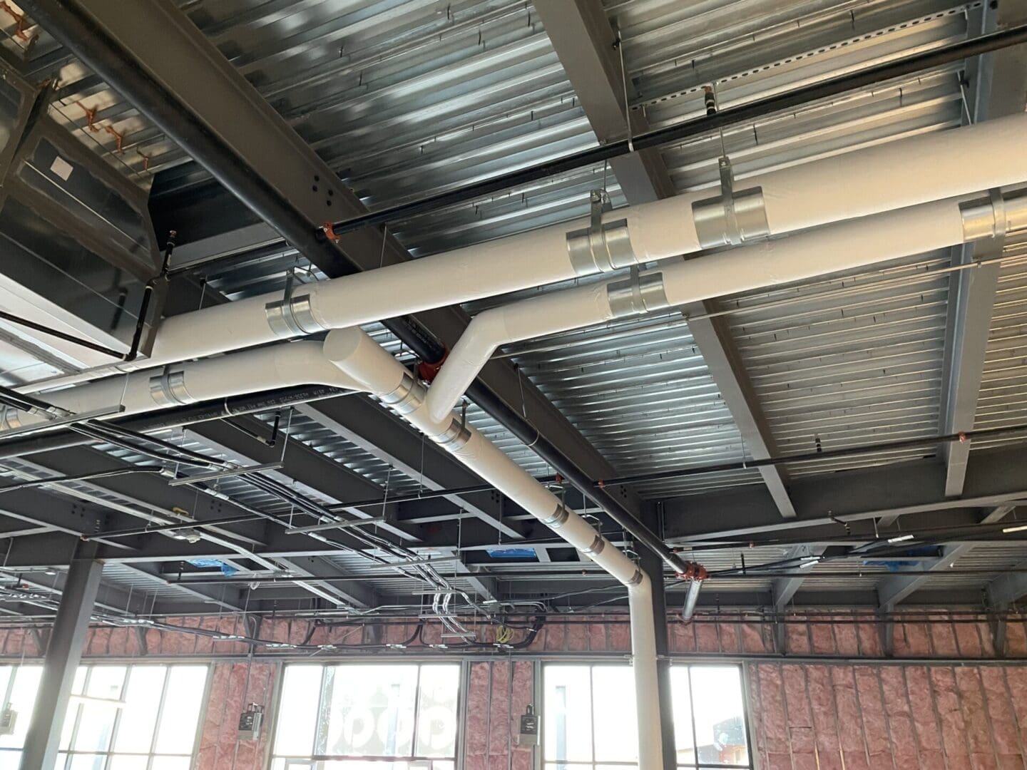 A ceiling with pipes and wires hanging from it.