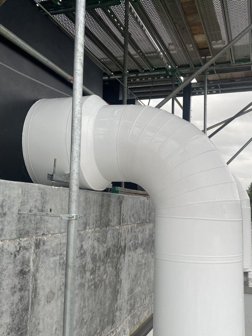 A white pipe is attached to the side of a building.